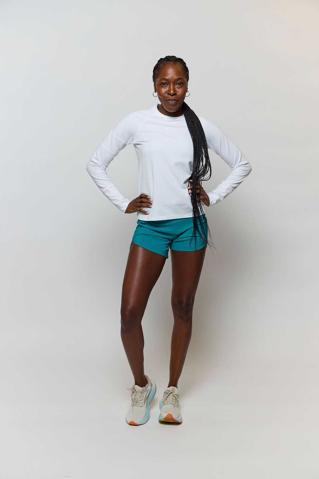 Full-length front view of a white Foudy 2.0 long-sleeve top worn with teal shorts