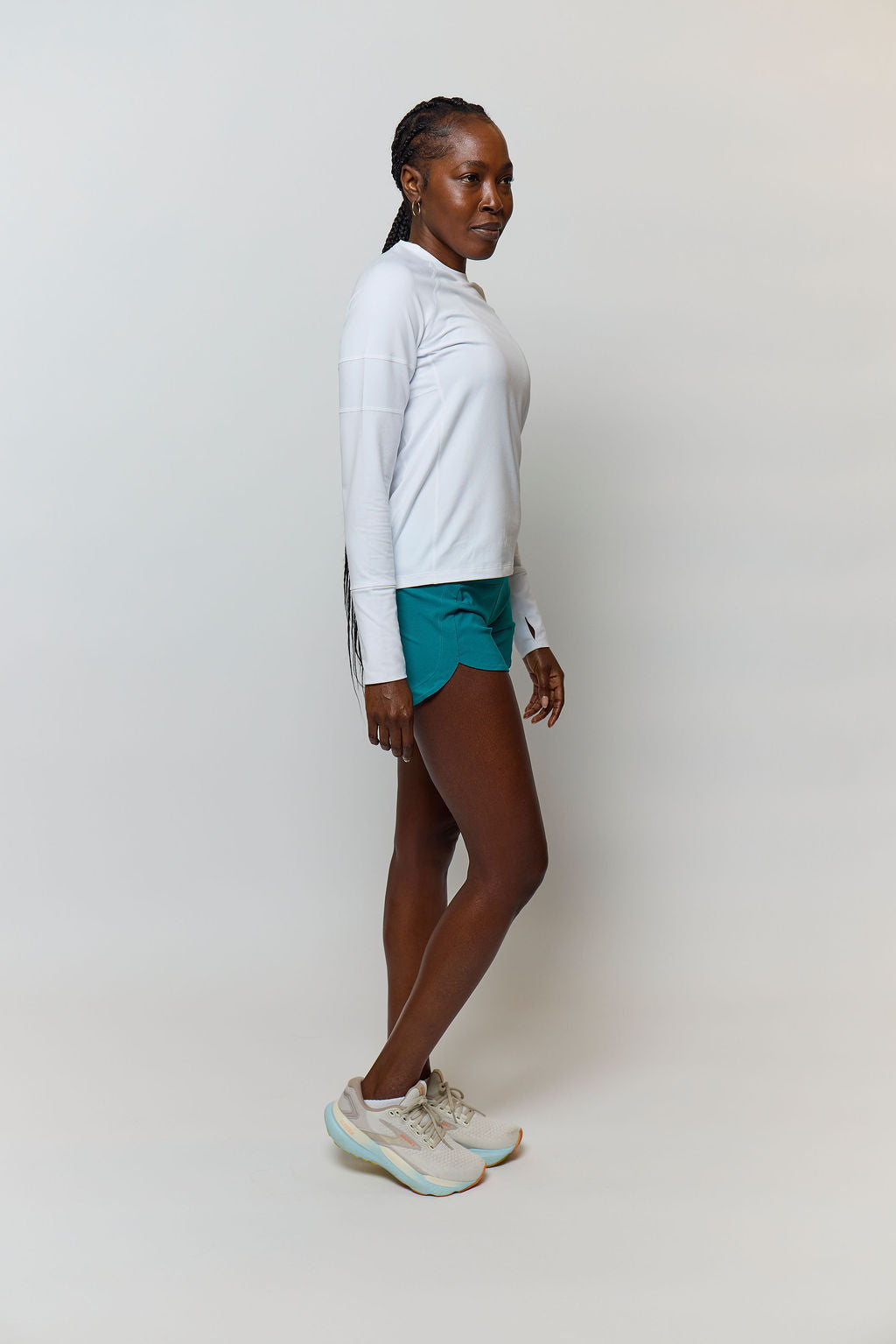 Side view of a white Foudy 2.0 long-sleeve top worn with teal shorts