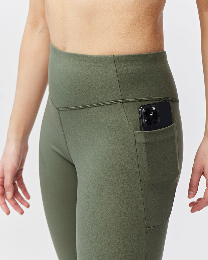 Olive green Go Again cropped leggings, close-up of the side pocket holding a phone