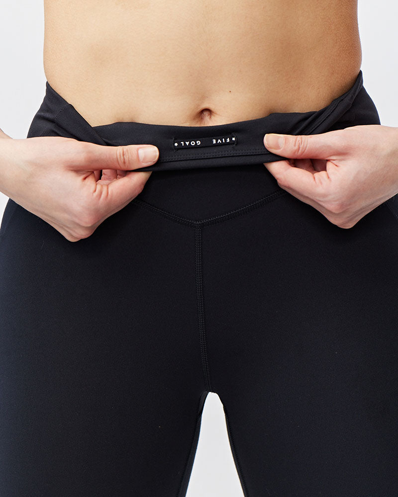 Black Go Again cropped leggings, close-up with the waistband folded outward to show the inner label