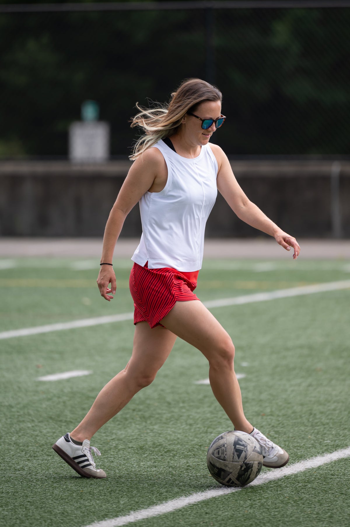 White Boxy Crop Tank worn while dribbling a soccer ball on a turf field