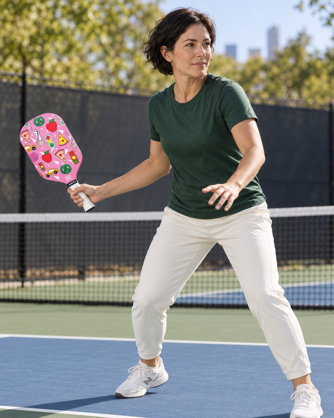AI-assisted pickleball scene of one adult woman forehand preparation using the pink ARTI NEW YORK paddle. Original supplier photos show product details.