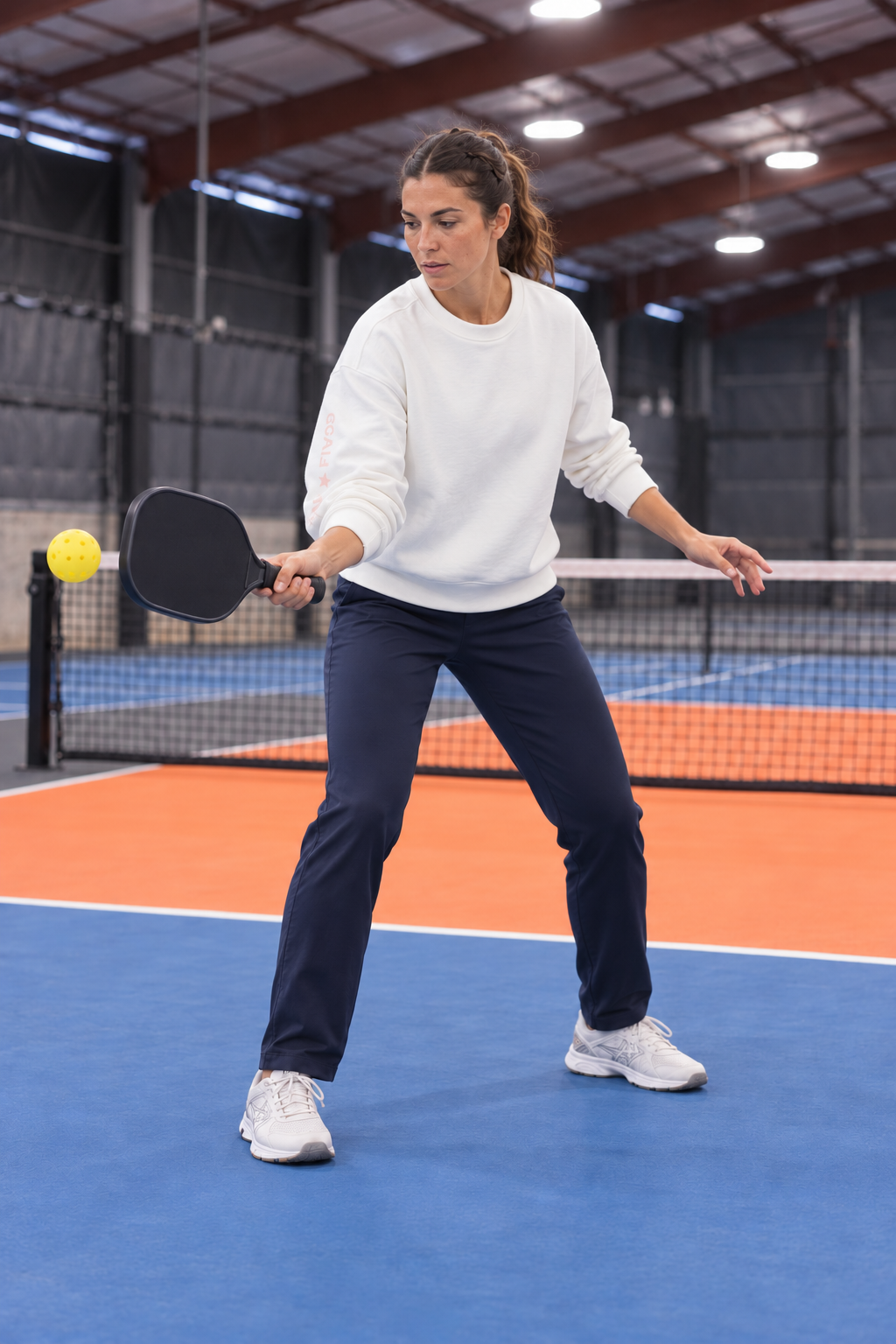 AI-assisted: adult woman in the White Freasy Crew playing a compact forehand on a Portland-region-inspired indoor pickleball court.