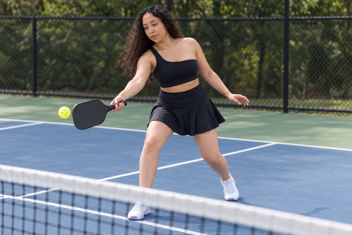 AI-assisted lifestyle image based on supplier photos; Black Rise skirt, front three-quarter view of a woman playing pickleball