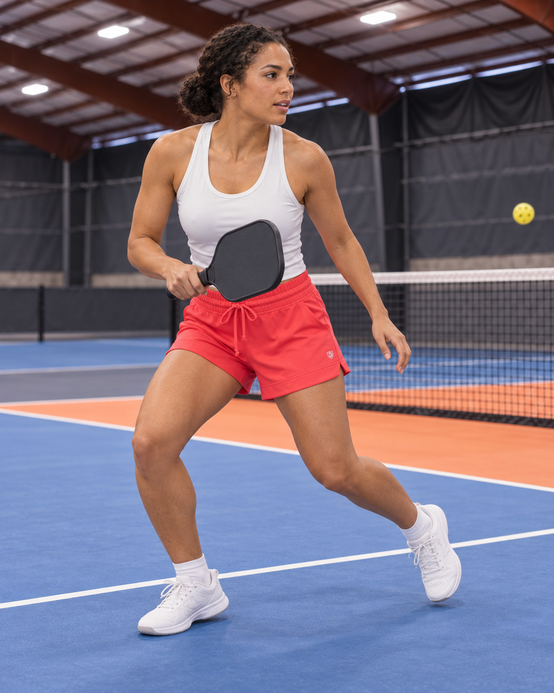 AI-assisted image of an adult woman recovering after a pickleball volley wearing G5 Advance 4.5" Knit Short in Hot Coral.